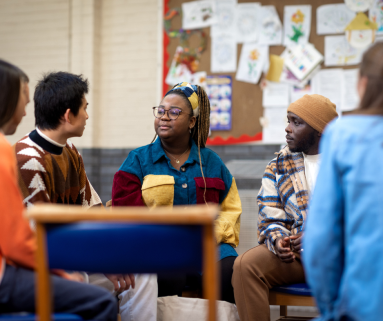 This shows a group of adults of all ages sitting in a community venue having an animated discussion.